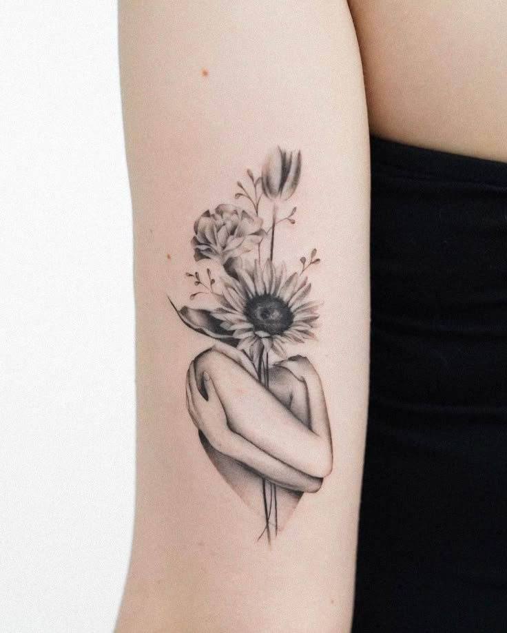 a black and white photo of a woman's arm with flowers in the middle