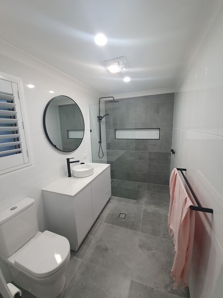 a bathroom with a toilet, sink and mirror