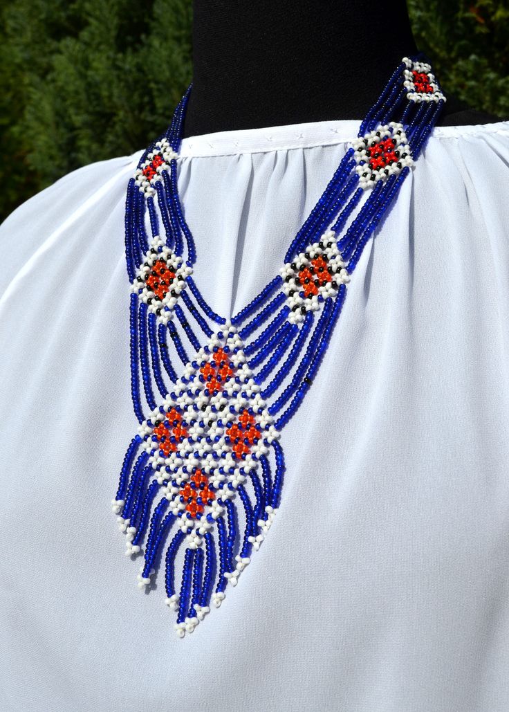 a blue and red beaded necklace on top of a white dress