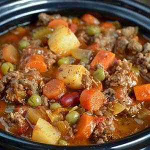 a crock pot filled with meat, vegetables and potatoes is ready to be eaten