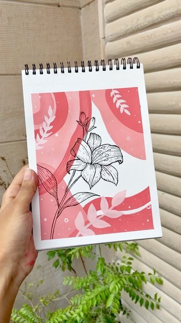 a hand holding up a notebook with flowers on it