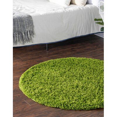 a green rug is on the floor next to a bed