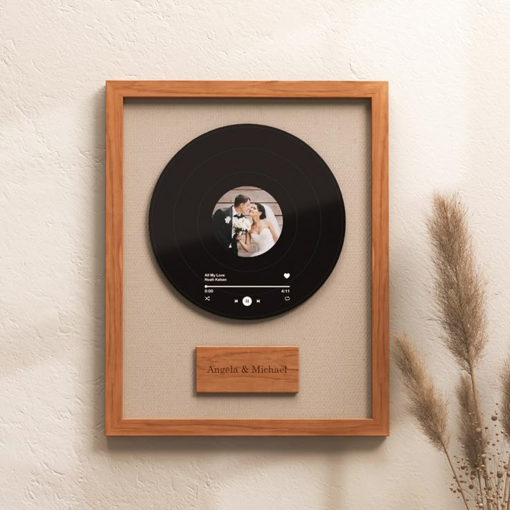 a wooden frame holding a black record with a photo on it and a plant in the corner