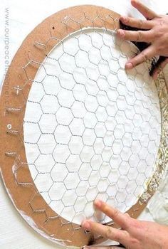 a person is making a paper plate with chicken wire on it, and another hand is holding something in front of the circle