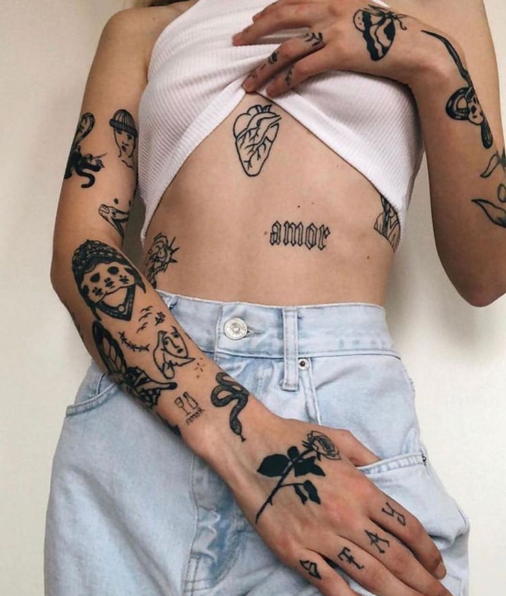 a woman with many tattoos on her arms and hands, holding onto the bottom half of her stomach