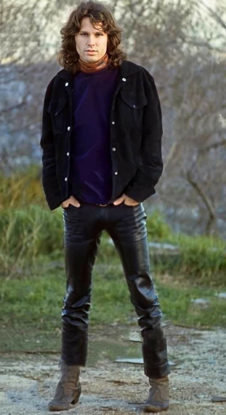 a man standing in the middle of a road wearing black leather pants and a purple shirt