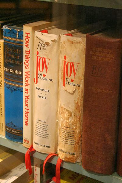 several books on a book shelf with red ribbon around the edges and one is closed