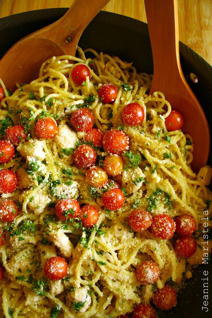 a bowl filled with pasta covered in sauce and topped with cherry tomatoes, parmesan cheese and fresh herbs