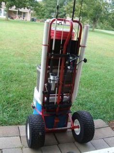 a red, white and blue cart sitting on top of a brick walkway next to grass