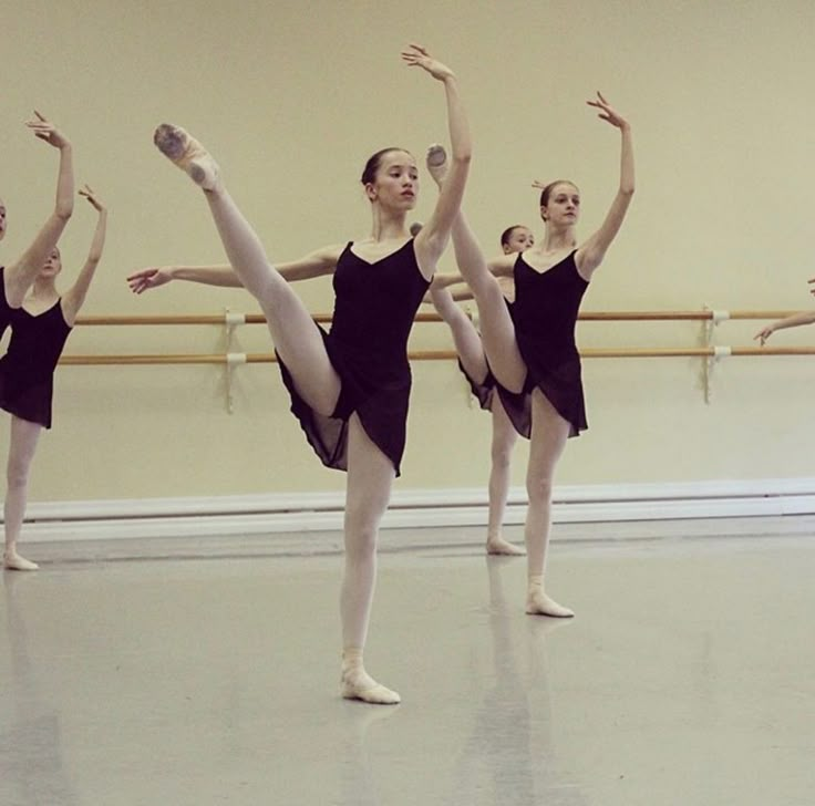 four ballerinas in black leotards are doing ballet moves