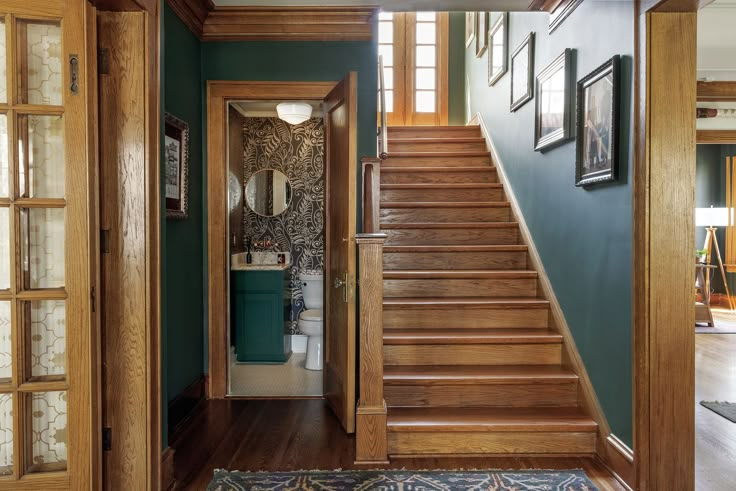 an entry way with stairs and pictures on the wall next to wooden doors, framed photographs above them