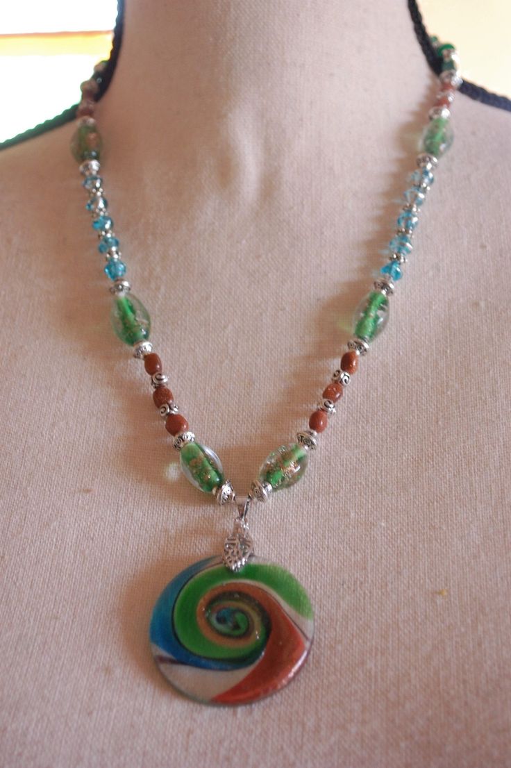 I designed and hand crafted this lovely hand beaded pendant necklace.  It has a beautiful lampworked glass pendant, and lampworked glass, natural stone, glass, and silver metallic beads.    The lampworked glass pendant and beads have a bit of sparkle - for just a touch of bling!  The colors are green, turquoise, bronze, silver, and clear/white.   This unique necklace measures 21 inches in length, and the pendant adds an additional 2.25 Inches.  It has a J-hook clasp, and is comfortable to wear. Ours is a non-smoking home. Colorful Beaded Necklace Of Recycled Glass For Gifts, Colorful Recycled Glass Beaded Necklace As Gift, Colorful Recycled Glass Beads Necklace For Jewelry Making, Colorful Beads Necklace For Jewelry Making, Unique Beaded Glass Necklaces, Unique Jewelry With Colorful Beads And Recycled Glass, Unique Recycled Glass Round Bead Necklaces, Colorful Beads Resin Jewelry Gift, Unique Recycled Glass Round Bead Necklace