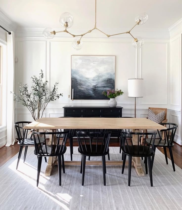 the dining room table is surrounded by black chairs and an art piece on the wall