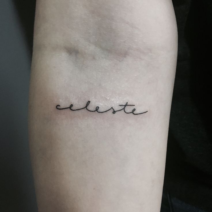 a small tattoo on the arm that reads, liberta in cursive writing