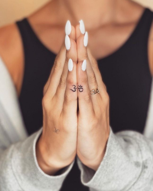 a woman with her hands folded in front of her face and two symbols on her fingers