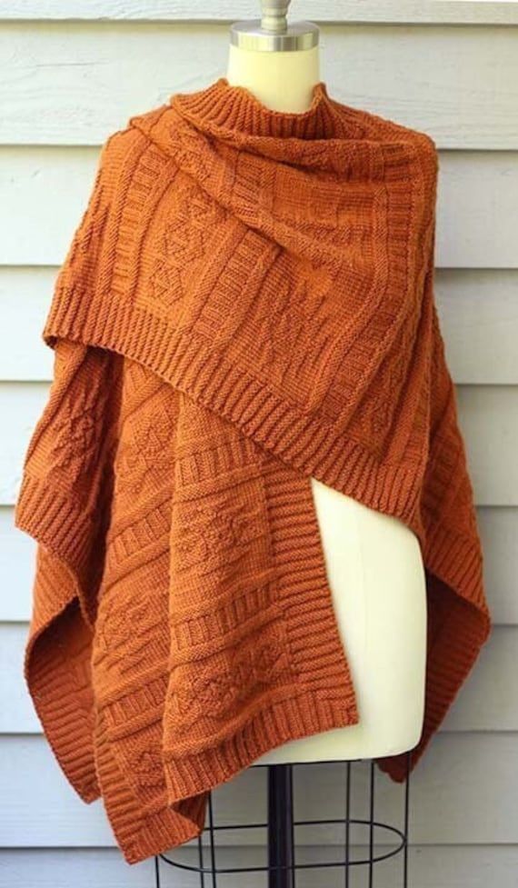 an orange knitted shawl sitting on top of a mannequin