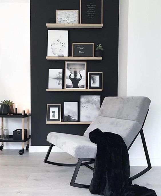 a black and white living room with pictures on the wall, a rocking chair and a rug