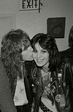 black and white photograph of two women kissing each other in front of an exit sign