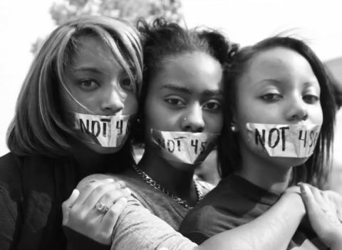 three girls with their faces taped to the words not by them on their face masks