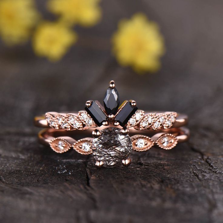 a black diamond engagement ring set on top of a piece of wood with yellow flowers in the background