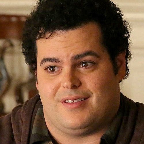 a close up of a person wearing a brown shirt and black hair with a smile on his face