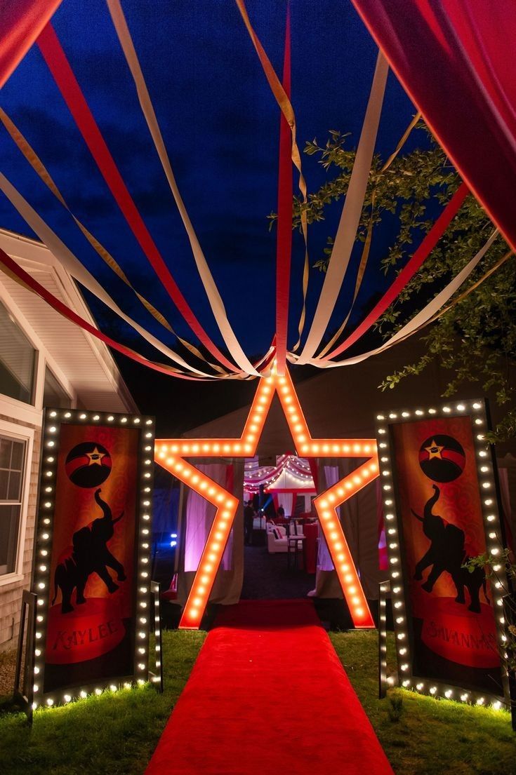 a red carpeted walkway leading to a star decorated entrance with lights on the sides