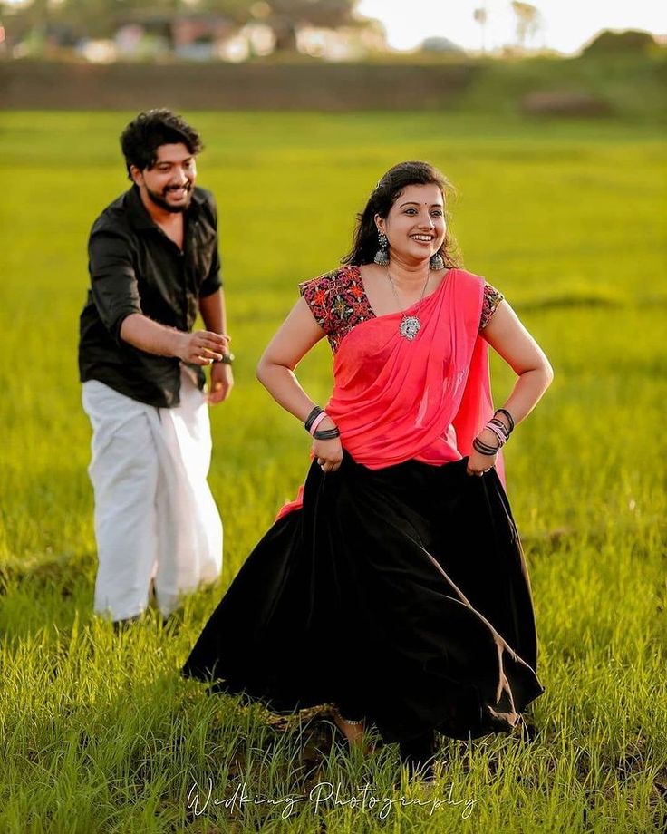 a man and woman are standing in the grass