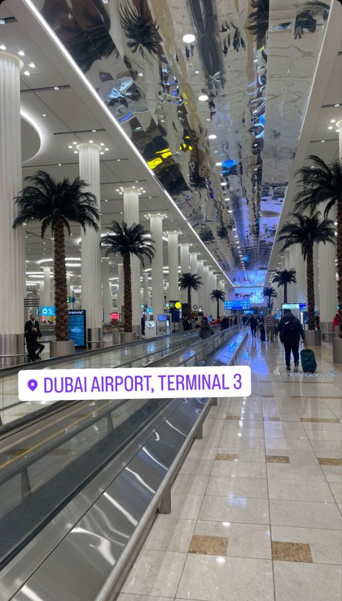 an airport terminal with palm trees and people walking through the walkways in front of them