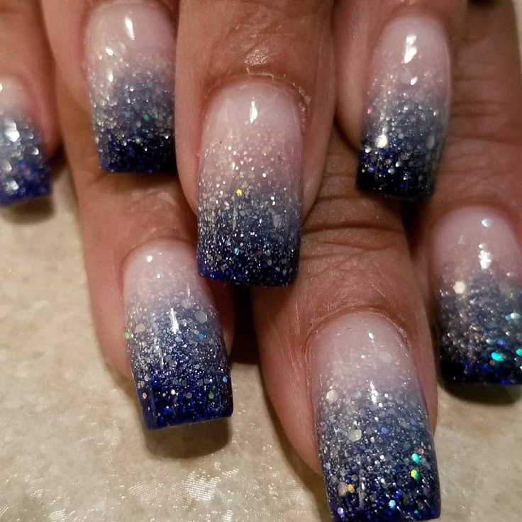 a woman's hand with blue and white nail polishes on her nails, which are covered in glitter