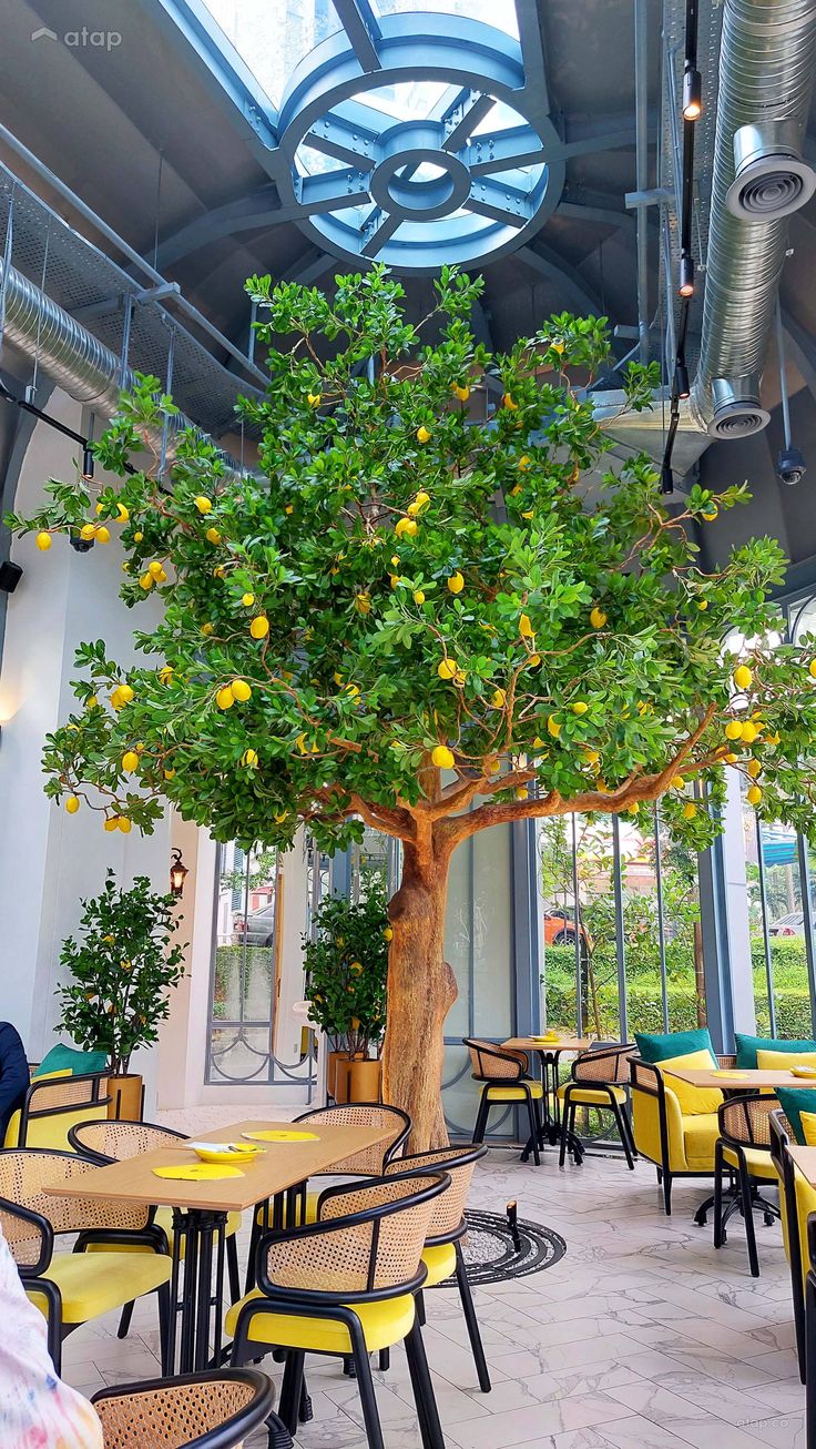 a large tree in the middle of a restaurant with lots of tables and chairs around it