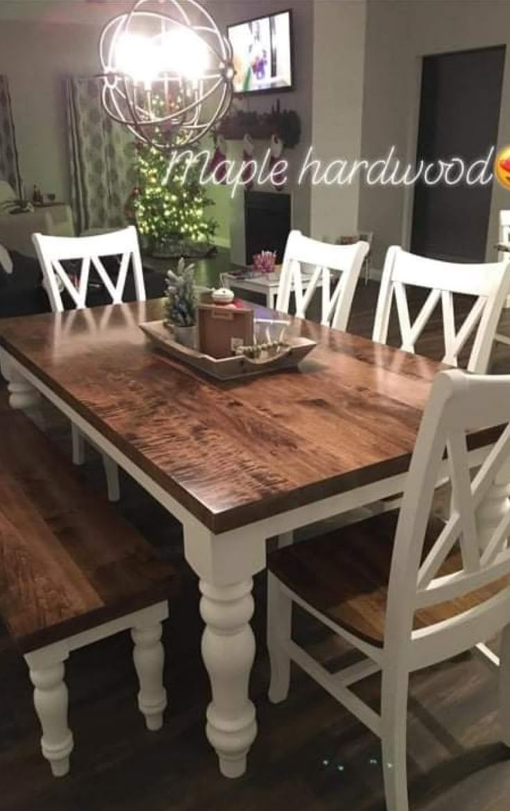 a dining room table with white chairs and a wooden centerpiece on top of it