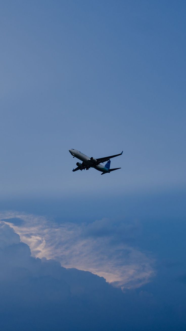 an airplane is flying in the sky with clouds around it and blue skies behind it