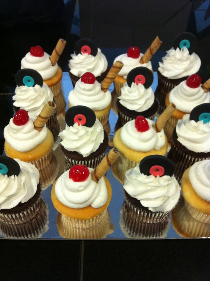 cupcakes with white frosting and red cherries on top are arranged in rows