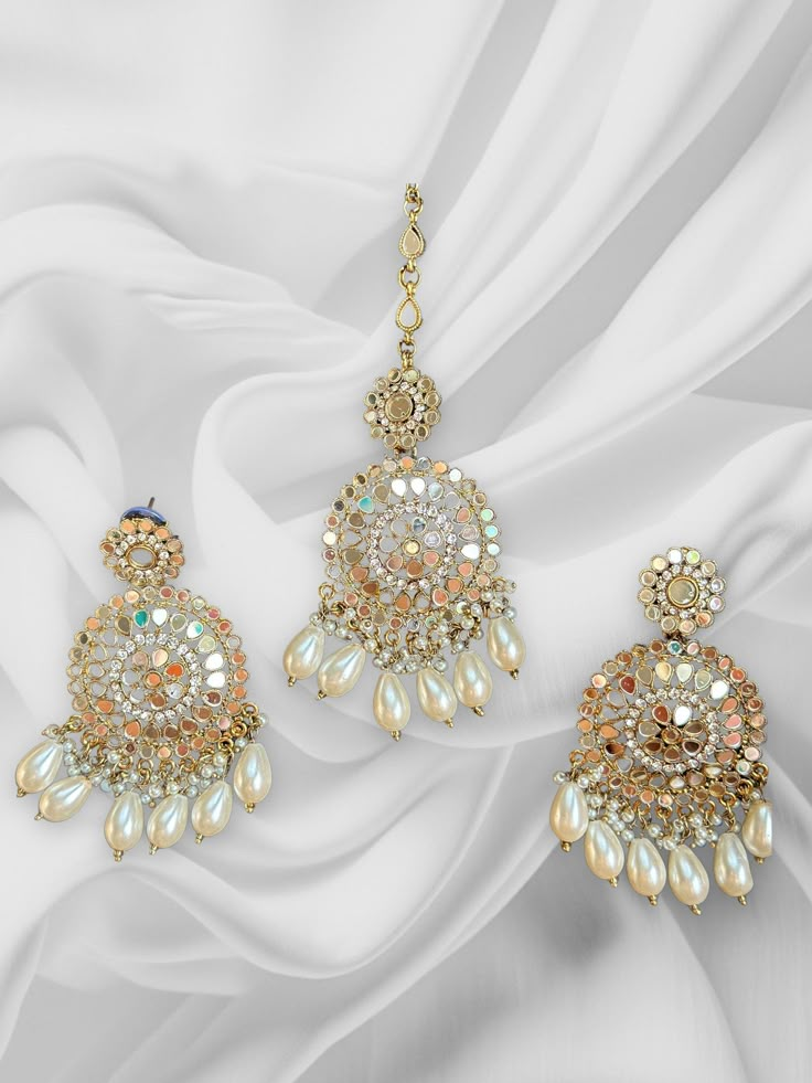 High Quality Silver and Pearl White finish with beaded work, this set is sure to be a perfect addition to any wardrobe! This mirror work tikka set is perfect for any bridesmaid, bride, sangeet or any occasion or event as a gift for any occasion as any one who loves jewelry will love this statement piece. It has beautiful colors that really make the set a statement piece. Product Details: * Maang tikka * Earrings  Free Shipping/Ready to Ship and available immediately if you place an order today! Fast and Free Shipping US Customers receive your order within 5-7 business days. This is the actual product picture so no surprises (please note colors may vary slightly due to image resolution etc)  To see more beautiful and unique pieces, please check out my shop: https://www.etsy.com/shop/MerakeT Luxury Chandbali Tikka For Festive Occasions, Luxury White Tikka For Festive Occasions, Elegant Luxury Tikka With Meenakari, Luxury Tikka With Latkans For Festivals, Luxury Bollywood Tikka For Diwali, Luxury Traditional Tikka For Festivals, White Earrings Indian, Luxury Elegant Tikka As A Gift, Luxury White Meenakari Tikka