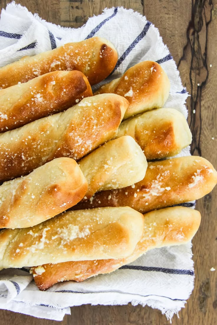 breadsticks are piled on top of each other with powdered sugar sprinkled on them