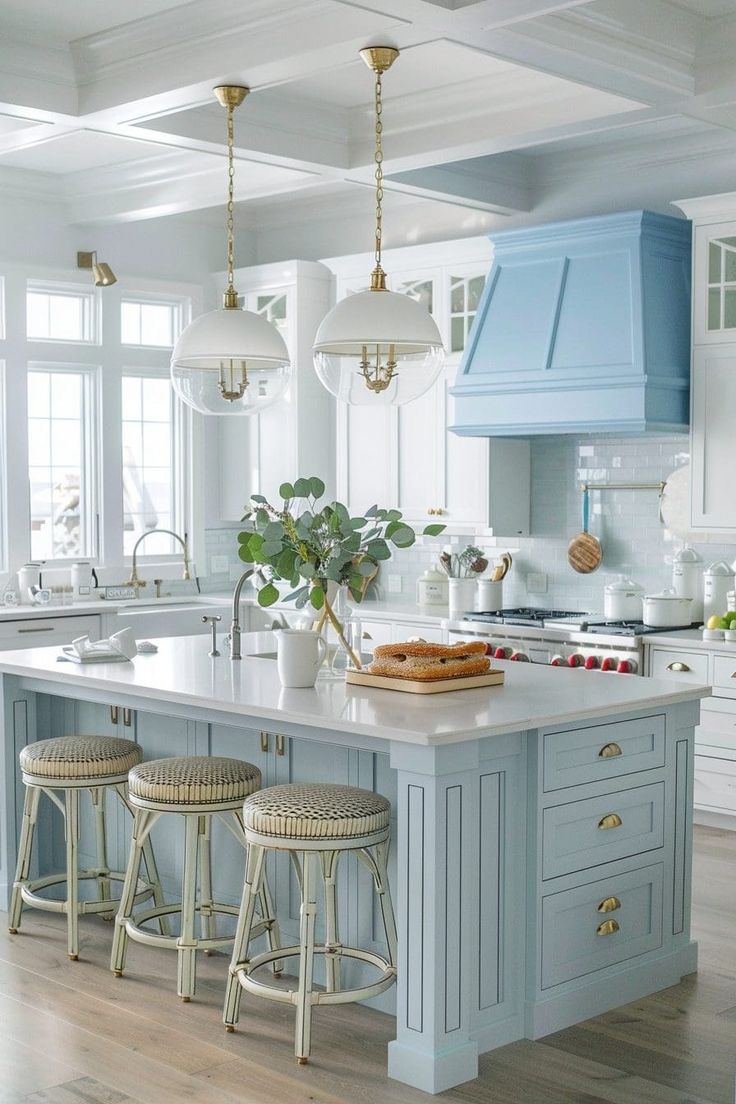 a blue kitchen island with stools in the middle and white cabinets on both sides