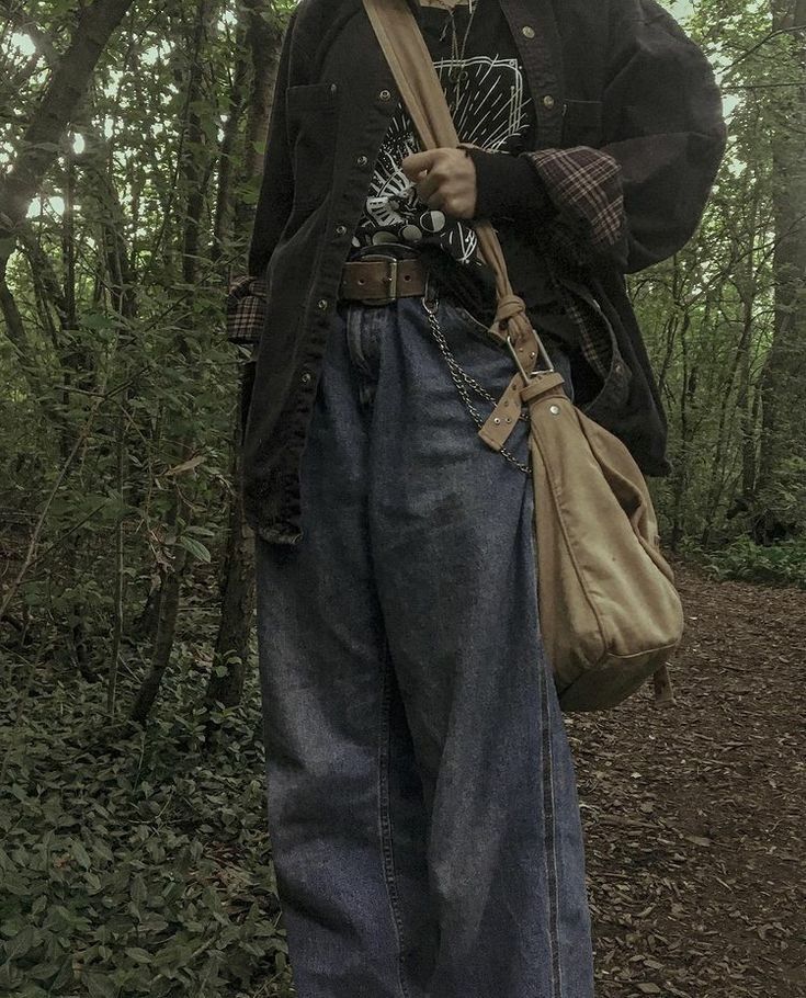 a person standing in the woods with an umbrella and bag on his shoulder, holding a cane