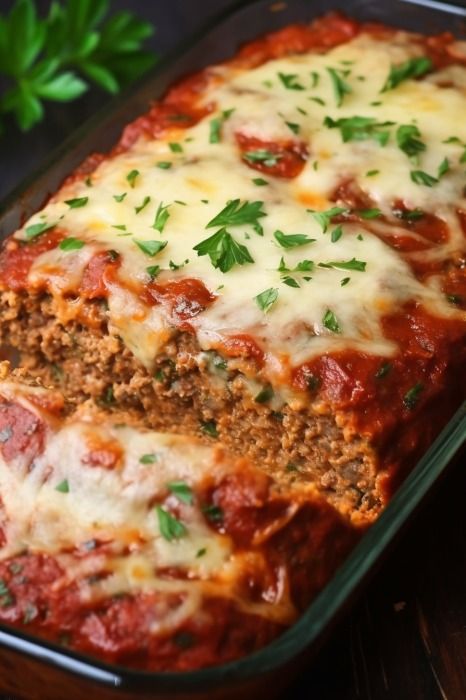 a casserole dish with meat, cheese and sauce in it on a wooden table