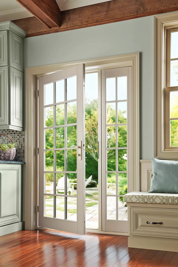 a living room with wooden floors and french doors leading to an outside patio area that has sliding glass doors on both sides