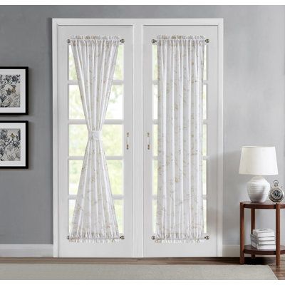 two white curtains hanging on the side of a door