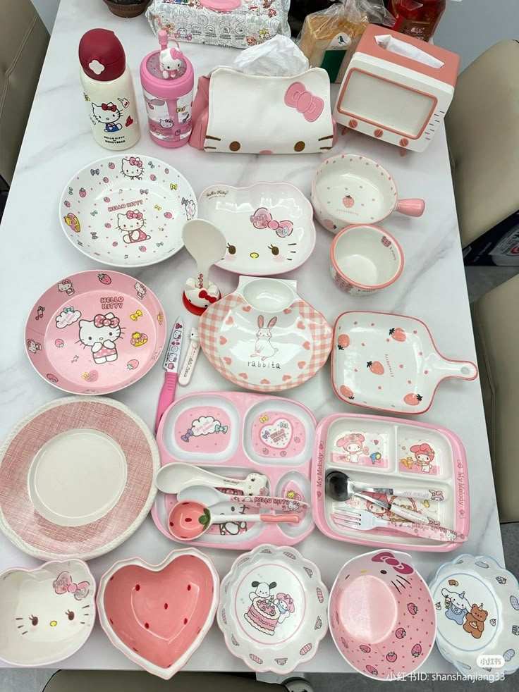 a table topped with lots of pink and white plates, cups and bowls filled with hello kitty dishes