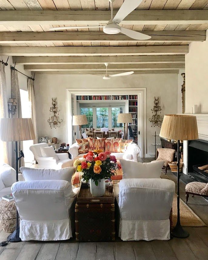 a living room filled with white furniture and lots of pillows on top of the couches