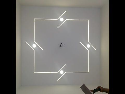 a white room with neon lights and a person on a laptop