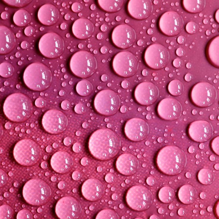 pink water drops on a surface that looks like it has been painted in different colors