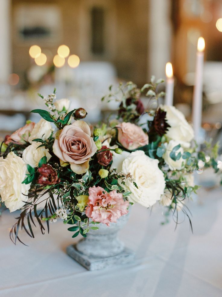 a vase filled with lots of flowers on top of a white table cloth covered table