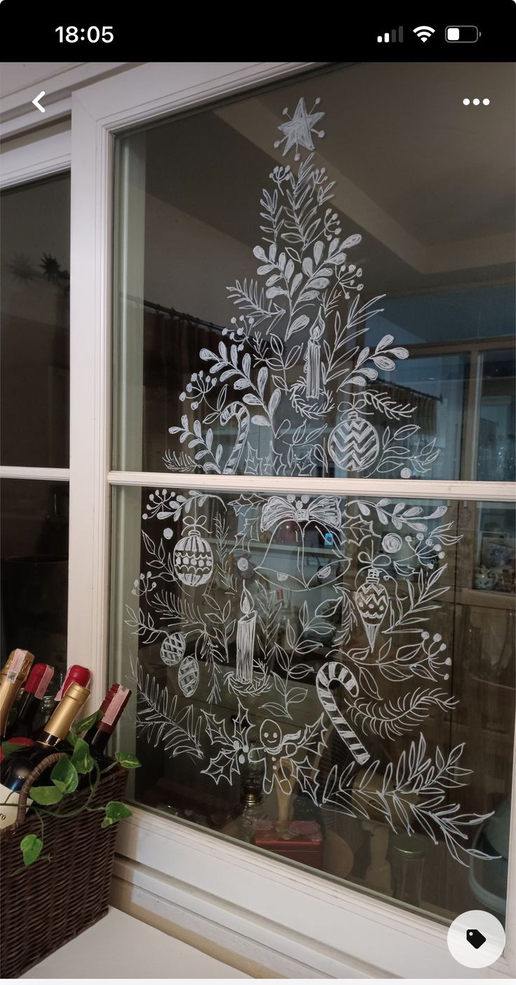 a christmas tree drawn on a window sill in front of a basket full of gifts