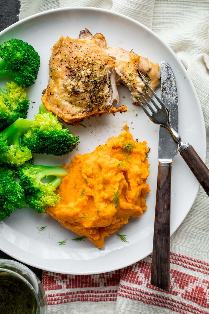 a white plate topped with chicken, mashed potatoes and broccoli next to a fork