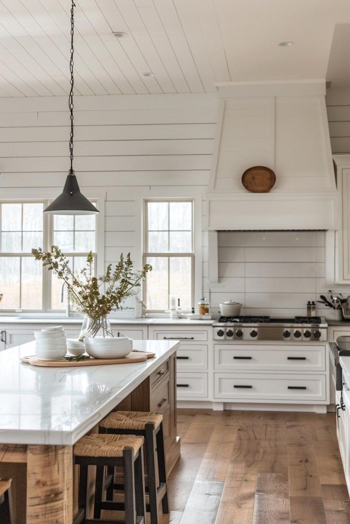 a large kitchen with white cabinets and wooden floors is pictured in this image, there are stools around the island