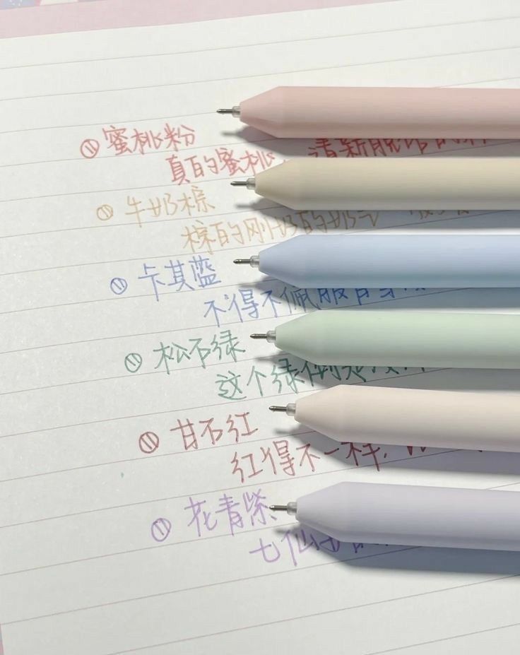 four different colored pens sitting on top of a piece of paper with writing in english and chinese