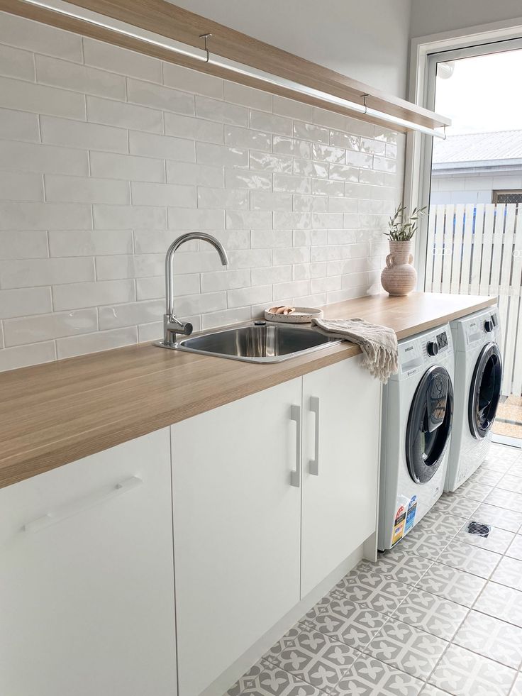 a washer and dryer sitting in a kitchen next to a window with an open door